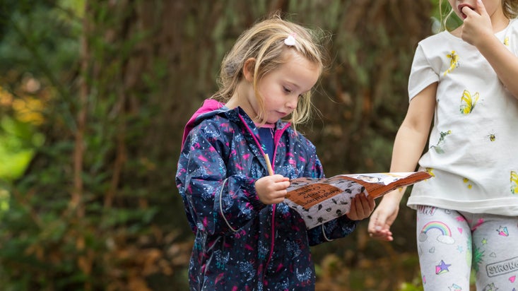 Two children in autumn woodland studying a trail sheet